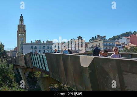 Montcada i Reixac. Spanien - 12. November 2024: Menschen überqueren in Moncada eine Fußgängerbrücke über den Ripoll-Fluss, wobei die städtische Infrastruktur hervorgehoben wird Stockfoto