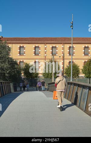 Montcada i Reixac. Spanien - 12. November 2024: Urbanes Leben auf einer Fußgängerbrücke über den Ripoll-Fluss in Moncada, mit Menschen, die überqueren und die Stockfoto