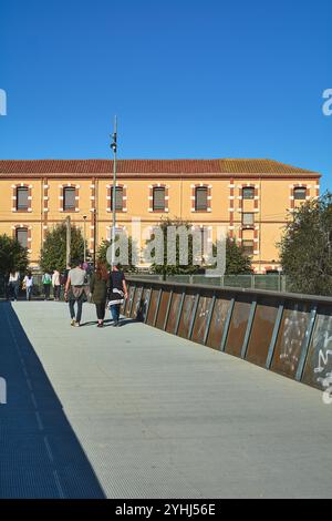 Montcada i Reixac. Spanien - 12. November 2024: Eine Fußgängerbrücke über den Ripoll-Fluss in Moncada, die Menschen zeigt, die über das Gebäude laufen, hochli Stockfoto