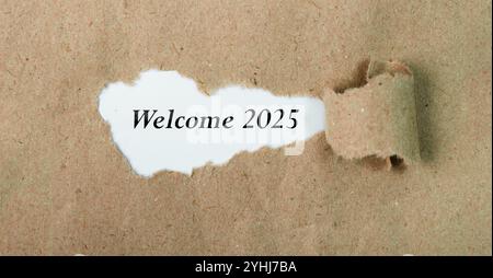 Begrüßungsbotschaft 2025 auf zerrissenem Papierstück mit braunem Hintergrund. Konzeptuelles Willkommenssymbol 2025. Kopierbereich. Stockfoto