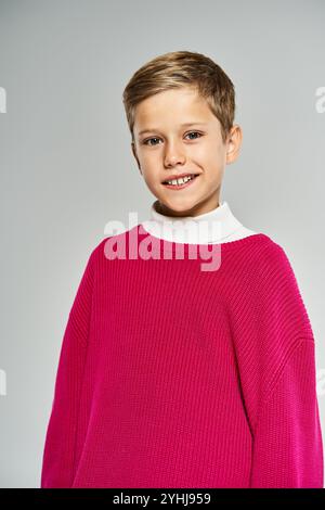 Ein fröhlicher Junge in warmer Winterkleidung versprüht Glück und Charme drinnen Stockfoto