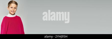 Ein fröhlicher Junge in gemütlicher Winterkleidung steht mit einem hellen Lächeln und strahlt Wärme aus. Stockfoto