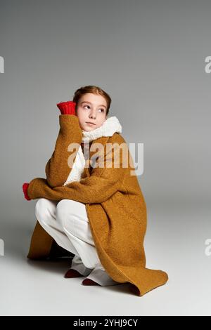 Ein Mädchen, warm gekleidet in einem hellen Mantel und Schal, reflektiert leise an einem kalten Winternachmittag. Stockfoto