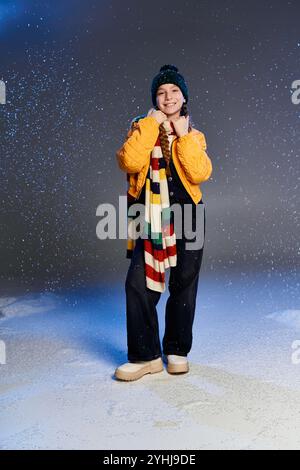 Ein Mädchen in warmer Winterkleidung glänzt vor Freude, während der Schnee um sie herum tanzt. Stockfoto