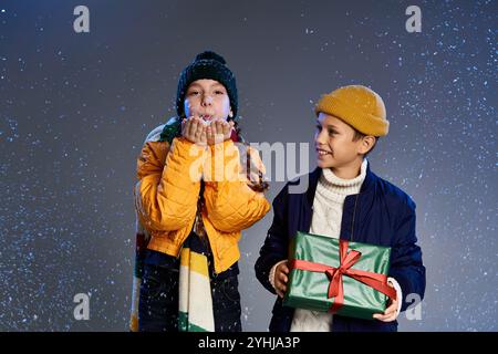 Zwei Kinder, die warm gekleidet sind, mit Geschenken, die sich in der Freude der Winterfeste erfreuen Stockfoto