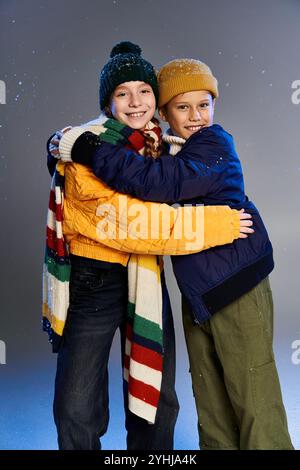Zwei fröhliche Kinder, die bunte Winterkleidung tragen, teilen sich eine warme Umarmung und feiern die Zweisamkeit. Stockfoto