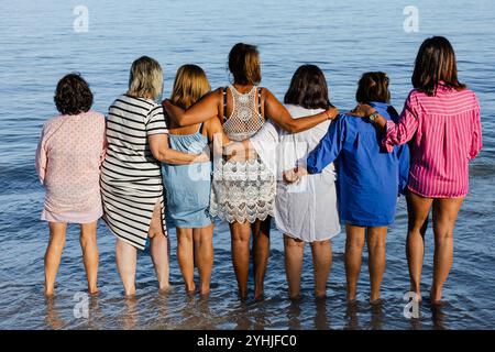 Rückansicht reifer Frauen, die sich an einem sonnigen Tag am Wasserrand binden Stockfoto