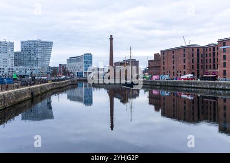 Die historischen alten Lagerhäuser des Albert Dock in Liverpool mit einem gemauerten Kamin und Street Food Fans spiegeln sich an einem bewölkten Tag im Wasser. Stockfoto