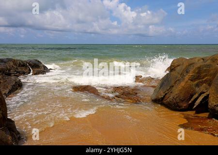 Leerer tropischer Strand mit großen Steinen, Blick auf gelben Sand und blaues Meer. Hintergrund für Reisen und Entspannung in der paradiesischen Natur Stockfoto