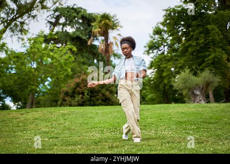 Eine Afrikanerin mit lockigem Haar, die eine Jeansjacke trägt, tanzt und genießt sich und strahlt Freude und Energie in ihren Bewegungen aus. Stockfoto