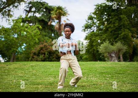 Eine Afrikanerin mit lockigem Haar, die eine Jeansjacke trägt, tanzt und genießt sich und strahlt Freude und Energie in ihren Bewegungen aus. Stockfoto