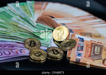 Goldene Bitcoin-Münzen sind neben einem Stapel Euro-Banknoten angeordnet und symbolisieren das Zusammenspiel zwischen traditioneller und digitaler Währung im modernen Finanzsektor Stockfoto