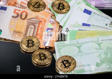 Goldene Bitcoin-Münzen sind neben einem Stapel Euro-Banknoten angeordnet und symbolisieren das Zusammenspiel zwischen traditioneller und digitaler Währung im modernen Finanzsektor Stockfoto