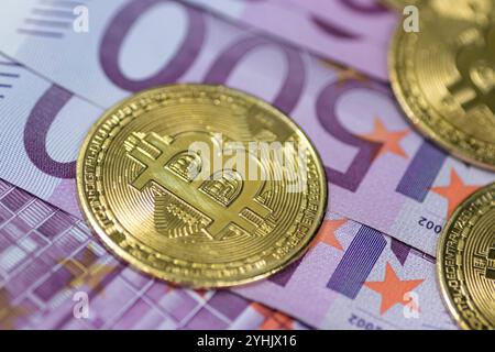 Goldene Bitcoin-Münzen sind neben einem Stapel Euro-Banknoten angeordnet und symbolisieren das Zusammenspiel zwischen traditioneller und digitaler Währung im modernen Finanzsektor Stockfoto