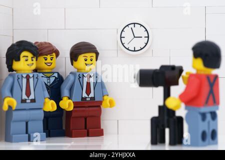 Tambow, Russische Föderation - 14. September 2024 Eine Minifigur des Lego-Fotografen fotografiert drei Lego-Geschäftsleute in ihrer von Stockfoto