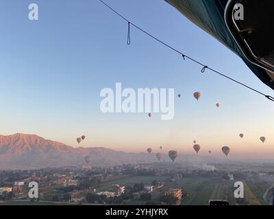 Heißluftballons fliegen im blauen Himmel in Ägypten mit Bergen im Hintergrund Stockfoto