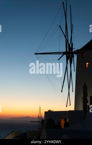 Silhouette einer Windmühle vor einem wunderschönen Sonnenuntergangshimmel über dem Meer im Dorf Oia während eines romantischen Abends auf der Insel Santorin in GRE Stockfoto