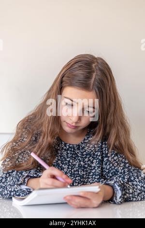 Ein trauriges Mädchen zieht ein Notizbuch ein. Die Hausaufgaben zu Hause. Stockfoto
