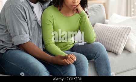 Ein Sorgender Schwarzer Mann Tröstet Seine Depressive Frau Zu Hause, Umarmen Und Unterstützen Stockfoto