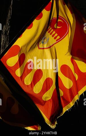 Gelbe und rote Flagge der contrada (traditionelles Viertel) von Santo Agnolo in Volterra, Toskana, Italien. Diese moderne Version der Flagge enthält das abnehmende Mond-Emblem der contrada und eine Darstellung des Heiligen Erzengels Michael. Stockfoto