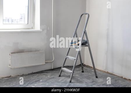 A folding ladder, a metal folding ladder in the room where the renovation is being done. Stockfoto