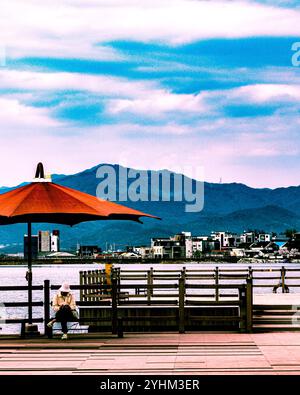 Blick auf den See mit rotem Regenschirm und Bergen im Hintergrund Stockfoto