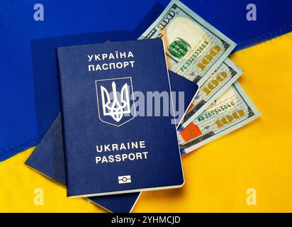 Pässe der Ukraine und Dollar auf dem Hintergrund der ukrainischen Flagge. Bargeld für das ukrainische Volk aus den Vereinigten Staaten im Zusammenhang Stockfoto