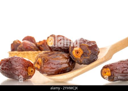 Mehrere süße getrocknete, entkernte Datteln mit Holzlöffel, Makro, isoliert auf weißem Hintergrund. Stockfoto