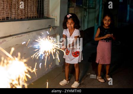 Zwei junge Mädchen feiern Diwali mit Glitzern und erhellen die Nacht mit Freude und Tradition. Stockfoto