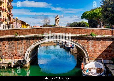 Backsteinbrücke aus dem 18. Jahrhundert mit einer Statue des Heiligen Johannes von Nepomuk, die einen Kanal in Livorno, Italien, überspannt. Stockfoto