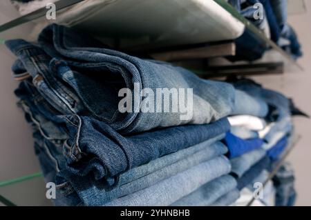 Gestapelter Denim zum Tragen. Eine Nahaufnahme gefalteter blauer Jeans im Einzelhandel. Perfekt für Mode- oder Einzelhandelsprojekte. Stockfoto