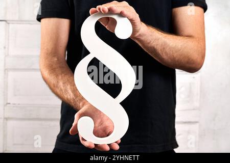 Bayern, Deutschland - 12. November 2024: Person mit einem Absatzschild. Symbol für Gesetze, Gesetzesänderungen, neue Gesetzesentwürfe und Gesetzesentwürfe in Deutschland. *** Person hält ein Paragraf-Zeichen. Symbol für Gesetzte, Gesetzesänderungen, neue Gesetzesentwürfe und Beschlüsse rund um das Gesetz in Deutschland. Stockfoto