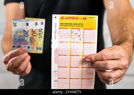 Bayern, Deutschland - 12. November 2024: Symbolisches Bild für Lotto 6 von 49: Lottogewinner hält Lottoscheine in der Hand neben Gewinngeld oder Euro-Banknoten. *** Symbolbild zu Lotto 6 aus 49. Lottogewinner hält Lotto-Schein, bzw. Spielschein in der Hand neben Geld-gewinn, bzw. Euro-Banknoten. Stockfoto