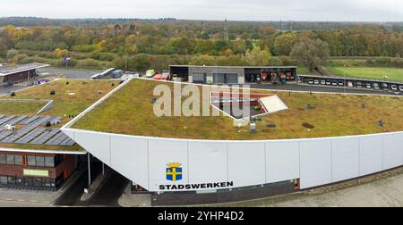 OLDENZAAL, NIEDERLANDE - 10. NOVEMBER 2024: Aus der Vogelperspektive auf das mit Gras, Pflanzen und Solarpaneelen überdachte Dach des städtischen Werkes. Stockfoto