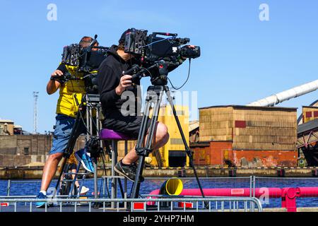 Zwei Videooperatoren mit professionellen Videokameras auf Stativen filmen das Ereignis mit blauem Himmel Stockfoto