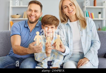 Glückliches lächelndes Familienpaar, kleiner Sohn, der mit Holzfiguren spielt, Eltern und Kind Stockfoto