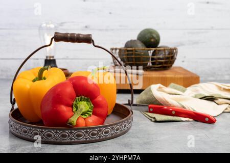 Rote und gelbe Paprika in einem Korb mit Avacados im Hintergrund auf der Küchenzeile Stockfoto
