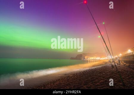 Aurora Borealis über Etretat Frankreich: Farbenfroher Nachthimmel und Angelruten am Strand Stockfoto