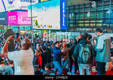 Der geschäftige Times Square in New York City mit vielen Touristen, die Selfies und Fotos machen, umgeben von lebhaften Plakaten bei Nacht. New York. USA. Stockfoto