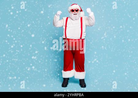 Volle Länge Foto von Fett lustig Santa Claus mit großen Bauch heben Fäuste ja das Gefühl der Stärke starke haben Weihnachtsfeier tragen rote Kappe Schrei Stockfoto