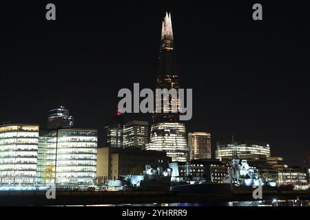 Der Shard Wolkenkratzer mit der HMS Belfast, der nachts an der Themse im Vordergrund verankert ist Stockfoto