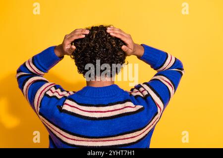 Foto-Porträt des hübschen jungen männlichen Rückansicht Touch Haarkopf tragen trendiges blau gestreiftes Outfit isoliert auf gelbem Hintergrund Stockfoto