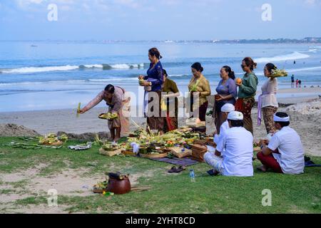 Kuta Beach, Bali, Indonesien - 8. November 2024: Religiöse hinduistische Zeremonie mit Frauen in traditioneller Kleidung, die Opfer und Opfer bringen. Stockfoto