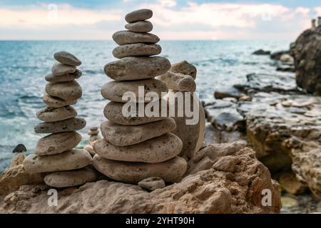 Stone Cairns Beach Ocean Küste Stone cairns liegt auf einem Felsvorsprung mit Blick auf ein blaues Meer mit bewölktem Himmel. Stockfoto