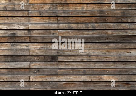 Eine Kollektion verwitterter Holzdielen zeigt einen rustikalen Charme und hebt verschiedene Brauntöne und Texturen in natürlichem Licht gegen eine neutrale Farbe hervor Stockfoto