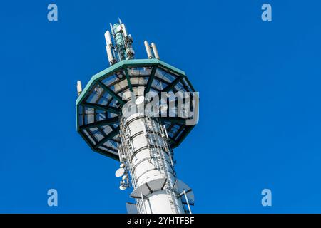 Ein hoher Telekommunikationsturm mit mehreren Antennen reicht zum klaren blauen Himmel und zeigt moderne Technologie in einer malerischen Umgebung im Freien. Stockfoto