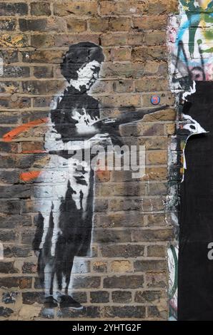 Frau mit einem Maschinengewehr Wall Street Art Graffiti, direkt an der Brick Lane, Spitalfields, East End London, England, UK 2024 2020s, UK HOMER SYKES. Stockfoto