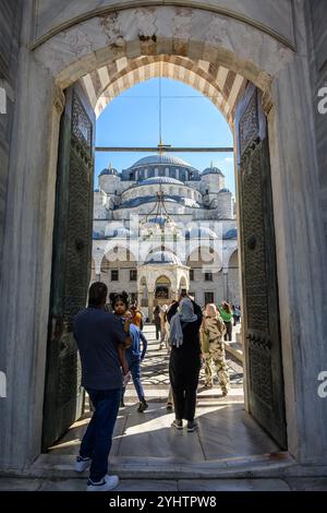 24/10/2024. Die Blaue Moschee, Istanbul, Türkei. Besucher betreten und verlassen den Innenhof. Die Blaue Moschee, offiziell Sultan Ahmed Moschee (türkisch Sultan Ahmet Camii), ist eine historische Moschee aus der osmanischen Zeit in Istanbul. Sie wurde zwischen 1609 und 1617 unter der Herrschaft von Ahmed I. errichtet und ist heute noch eine funktionierende Moschee. Es zieht auch eine große Anzahl von Touristen an und ist eines der bekanntesten und beliebtesten Denkmäler der osmanischen Architektur. Die Moschee hat einen klassischen osmanischen Grundriss mit einer zentralen Kuppel, die von vier Halbkuppeln über dem Gebetssaal umgeben ist. Es ist Fronte Stockfoto