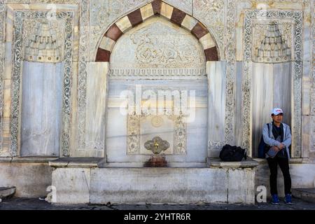 24/10/2024. Istanbul, Türkei. Ein Tourist rastet auf dem Brunnen von Sultan Ahmed III. Auf dem großen Platz vor dem Kaisertor des Topkapı-Palastes in Istanbul, Türkei. Sie wurde 1728 unter dem osmanischen Sultan Ahmed III. Im Stil der Tulpenzeit erbaut. Es war ein soziales Zentrum und Versammlungsort während der osmanischen Zeit Konstantinopels. Foto: © Simon Grosset Stockfoto