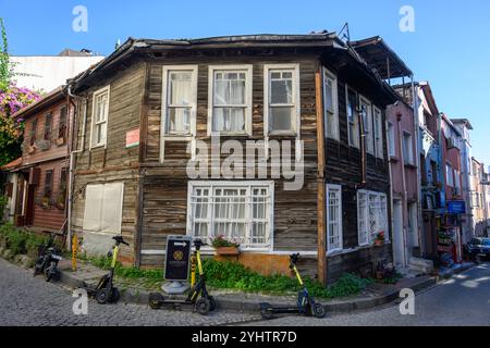 24/10/2024.Fatih, Istanbul, Türkei. Moderne Elektroroller parkten vor einem traditionellen Holzhaus. Foto: © Simon Grosset Stockfoto